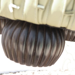 K&ouml;nnte beinhalten: Nahaufnahme eines braunen, gerippten, runden M&ouml;belbeins. Das Bein besteht aus einem strukturierten Material und hat eine leicht abgerundete Form.