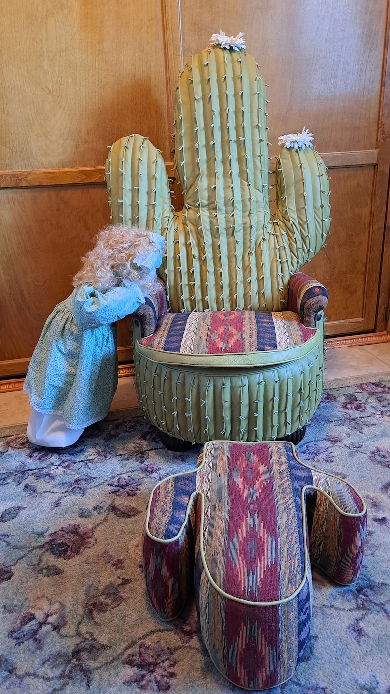 K&ouml;nnte beinhalten: Ein gr&uuml;ner Kaktus-f&ouml;rmiger Stuhl mit einem Kissen im S&uuml;dwest-Muster und einem passenden Fu&szlig;hocker. Der Stuhl hat eine wei&szlig;e Blume oben und der Fu&szlig;hocker hat ein &auml;hnliches Muster wie das Kissen.