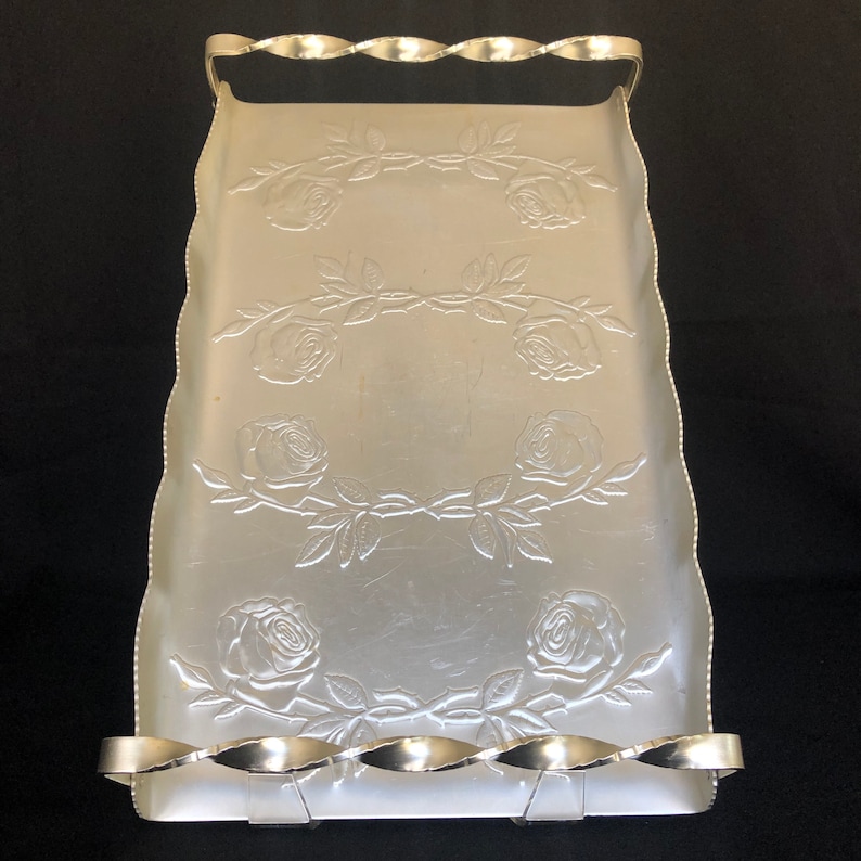 May include: Silver serving tray with a decorative embossed rose pattern and a twisted wire handle.