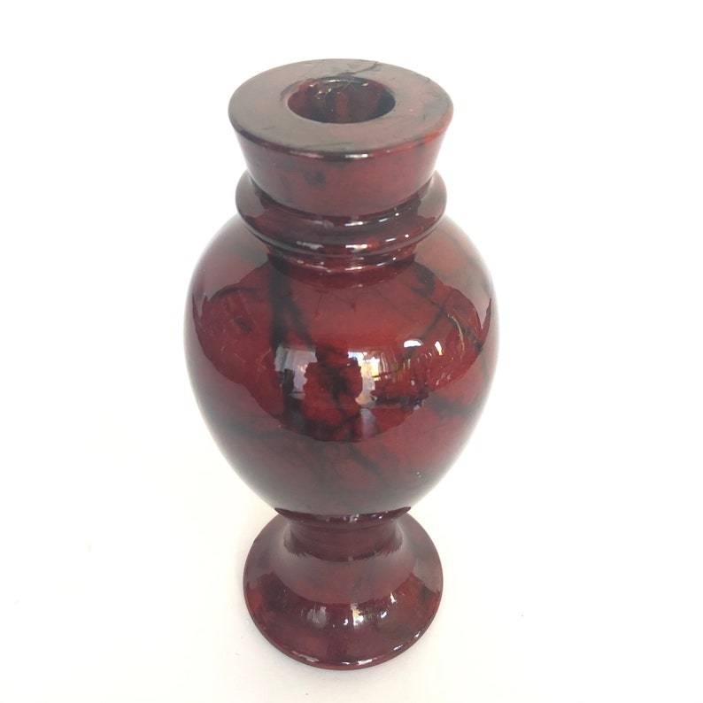 May include: A red and black marble vase with a wide base and a narrow neck. The vase has a glossy finish.