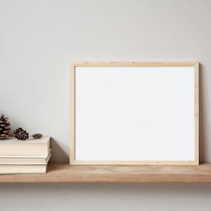 May include: A wooden shelf with a framed picture, a stack of books, pine cones, and a wooden toy truck. The shelf is against a light grey wall.