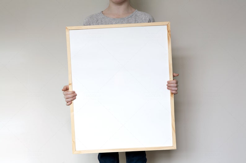 May include: A person holding a blank white framed poster in front of their body.