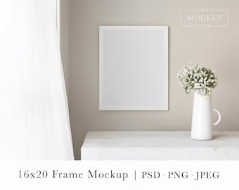 May include: A white picture frame mockup with a white mat, sitting on a white table with a white vase of white flowers. The frame is 16x20 inches.