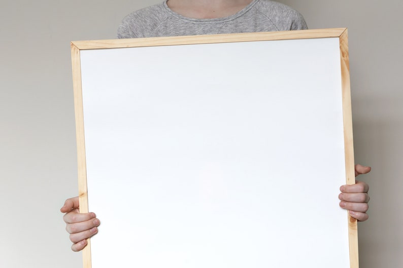 May include: A person holding a white framed whiteboard.