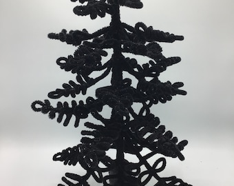May include: A black velvet Christmas tree with a black base. The tree is made of twisted pipe cleaners and is about 30 cm tall.