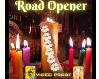 May include: A collection of lit candles in various colours including orange, yellow, purple, red, and green, surrounding a central pillar candle. A vertical strip with white flower illustrations is placed on the pillar candle. Text reads Road Opener and VIDEO PROOF, with The Fool and Opportunity tarot cards visible.