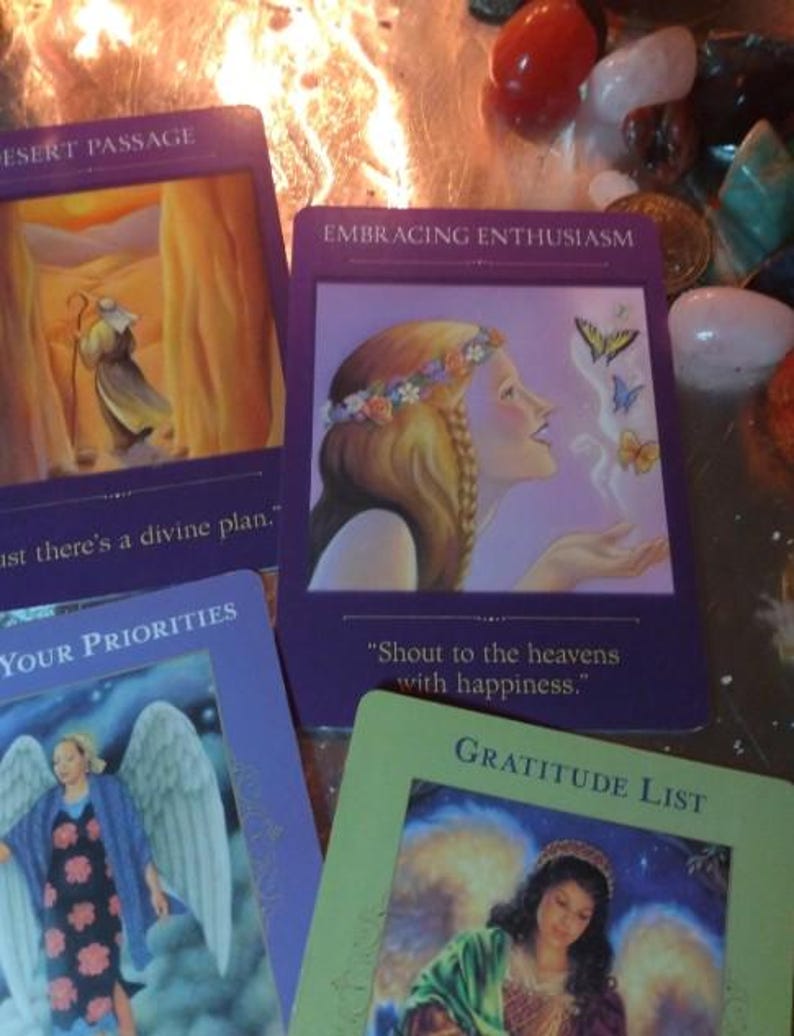 May include: Four rectangular oracle cards with purple and green borders. One card shows a person with a flower crown and butterflies, labelled Embracing Enthusiasm. Another shows a desert scene, labelled Desert Passage. Others show angels.
