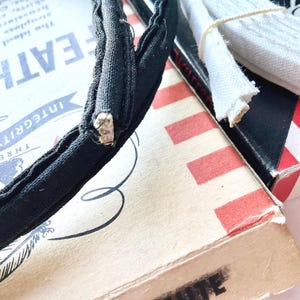 May include: A black headband with a white seam, a white fabric trim, and a red and white striped box with the text "Integrity" and "Three Oaks" printed on it.