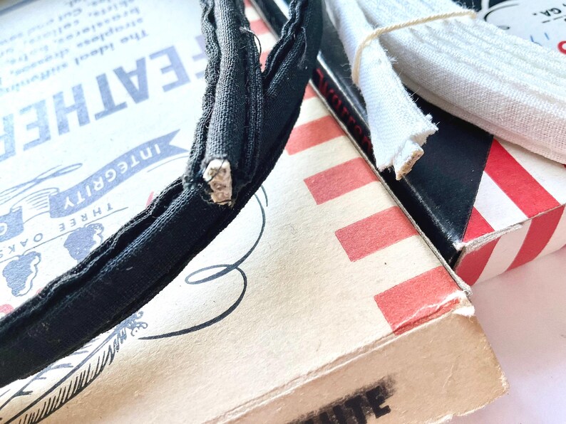 May include: A black headband with a white seam, a white fabric trim, and a red and white striped box with the text "Integrity" and "Three Oaks" printed on it.