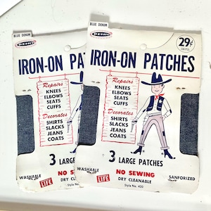 May include: Two vintage iron-on patches for denim repairs and decoration. Each package features a blue denim patch and a cartoon cowboy illustration. Text includes "Iron-On Patches," "Repairs," "Decorates," and "3 Large Patches." The patches are washable and dry cleanable.