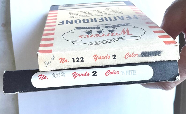 May include: Two boxes of white Featherbone thread, labeled "Warren's" with the number "122", "Yards 2", and "Color WHITE".