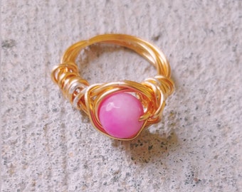 May include: A gold wire wrapped ring with a pink gemstone.