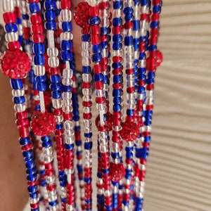 May include: A beaded necklace with red, white, and blue beads. The beads are arranged in a pattern that resembles the American flag.