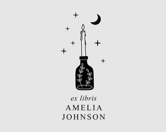 May include: A black and white line art illustration featuring a candle in a bottle, surrounded by stars and a crescent moon. Below the bottle, the text reads ex libris AMELIA JOHNSON in a clean, serif font, centered on a light gray background.