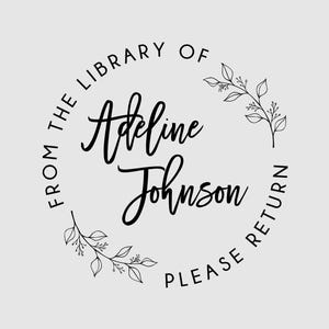 May include: A circular black ink stamp design on a light gray background. The text reads FROM THE LIBRARY OF Adeline Johnson PLEASE RETURN. The design features two delicate black line art leaf sprigs positioned along the circular border.