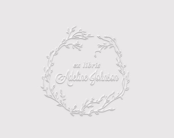 May include: A white graphic design on a light grey background featuring a circular wreath made of thin, stylised branches and leaves. Centred within the wreath is the text "ex libris" in a simple font above the name "Adeline Johnson" in script.