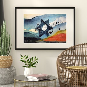 May include: A framed watercolor painting of a blue Star of David against a background of blue, green, yellow, and orange watercolor washes. The painting is in a black frame and is hanging on a white wall.