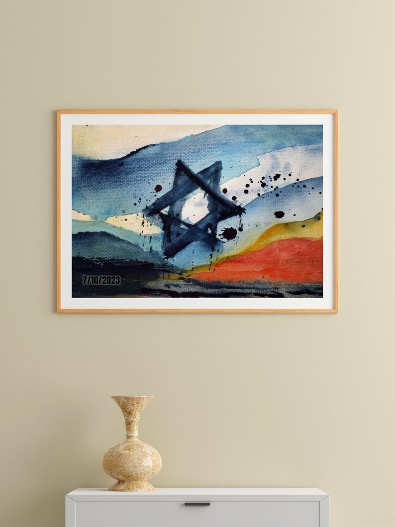May include: Abstract watercolor painting of a Star of David in blue, yellow, and red hues. The painting is framed and has the date "7/10/2023" in the bottom left corner.
