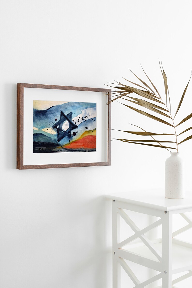May include: A framed watercolor painting of a blue Star of David with a red, yellow, and blue background. The painting is in a brown frame and is hanging on a white wall.