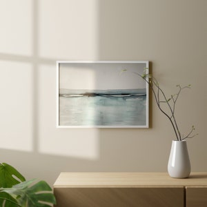 May include: A framed watercolor painting of a seascape with a light blue and gray color scheme. The painting depicts a horizon line with a dark blue band representing the water and a light blue sky above.