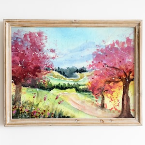 Könnte beinhalten: Aquarellmalerei einer Landschaft mit zwei rosa Bäumen im Vordergrund und einem grünen Hügel im Hintergrund.