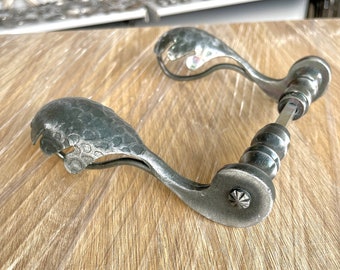 Galvanized antique door handle in the shape of a leaf.