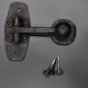 May include: A rustic, black metal latch with a decorative, faceted knob and three matching nails. The latch features a hinged design for secure closure. Ideal for cabinets, doors, or other woodworking projects.