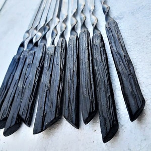 Peut inclure: Un ensemble de dix brochettes en métal noir avec des manches torsadés. Les brochettes sont en métal durable et sont parfaites pour griller.