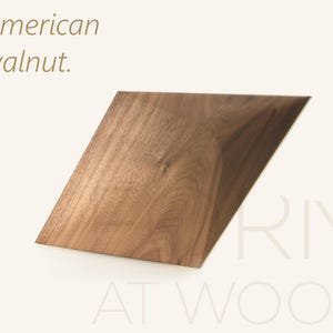 Op de afbeelding: Een geometrisch, piramidevormig object gemaakt van Amerikaans walnotenhout met een zichtbare natuurlijke houtnerf. De tekst 'American walnut.' staat in de linkerbovenhoek en de tekst 'RIMI AT WOOD' is rechtsonder zichtbaar.