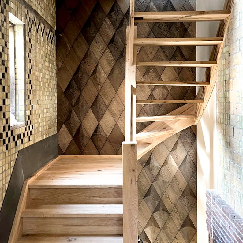 May include: Wooden staircase with light-colored steps and a matching handrail. The wall features a geometric pattern of diamond-shaped wooden panels in varying shades of brown. The adjacent wall is covered in light-colored tiles, and a small window is visible.