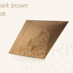 Op de afbeelding: Een vierkant houten bord gemaakt van donkerbruin eikenhout met een zichtbaar natuurlijk houtnerfpatroon. De tekst "Dark brown oak." staat in de linkerbovenhoek en de tekst "RIMI AT WOOD" staat in de rechterbenedenhoek.