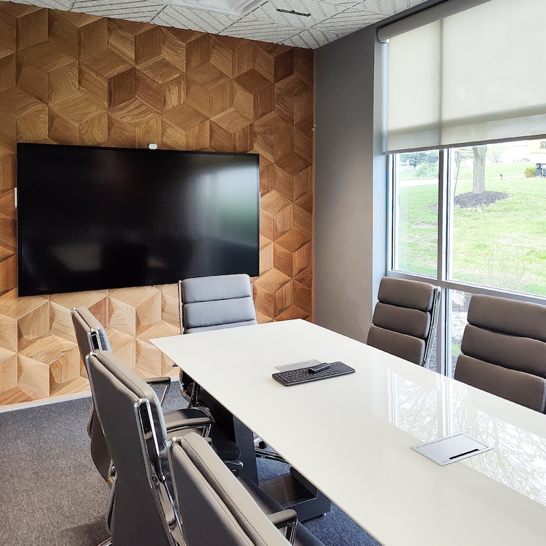 Modern conference room with a geometric wood accent wall featuring 3D wall panels in a natural finish. The textured wall art adds depth and style to the space, serving as both a decorative wood wall panel and a subtle sound diffuser. Perfect example of wall paneling and wood wall decor in office interior design.