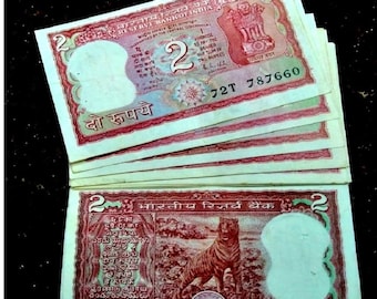 May include: A stack of vintage Indian two rupee banknotes featuring a tiger illustration and the text "भारतीय रिज़र्व बैंक" (Reserve Bank of India) in Hindi. The banknotes are in good condition and have a faded, vintage look.