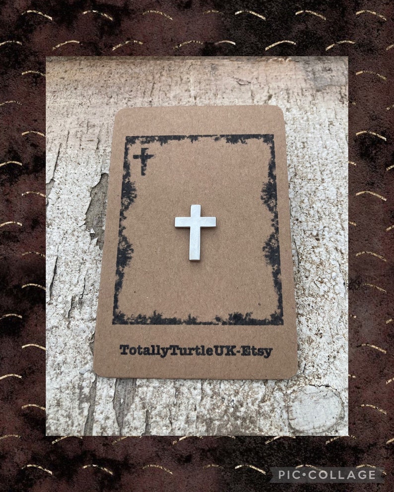 Puede incluir: Un amuleto de cruz plateado en una tarjeta marr&oacute;n con el texto "TotallyTurtleUK-Etsy".