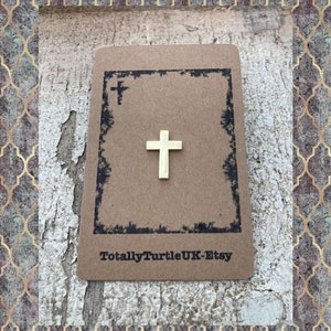 Puede incluir: Una peque&ntilde;a cruz dorada en una tarjeta marr&oacute;n con el texto "TotallyTurtleUK-Etsy".
