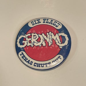 May include: A blue and red round pin with the text "Six Flags Geronimo Texas Chute Out" in white.