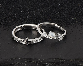 May include: Two silver rings with delicate floral designs. One ring features a white gemstone and the other has a small star-shaped accent.