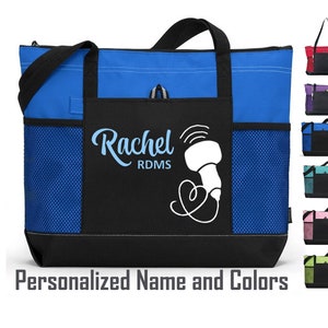 Könnte beinhalten: Eine blaue und schwarze Tragetasche mit einem Netzfach und einem personalisierten Design, das "Rachel RDMS" mit einer stilisierten Ultraschallsonde und einem Herzen sagt.