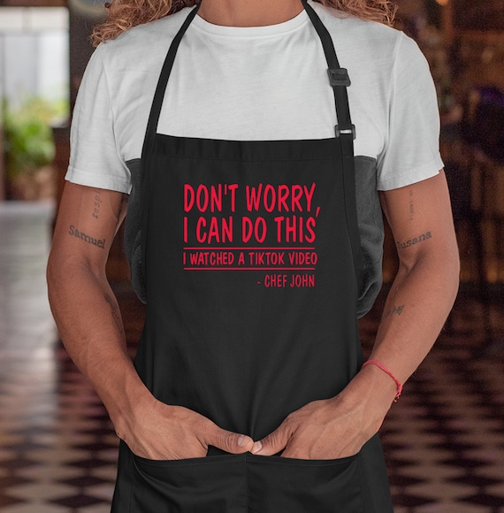 Donna di colore che indossa un grembiule in cucina e segue un video di  cucina online