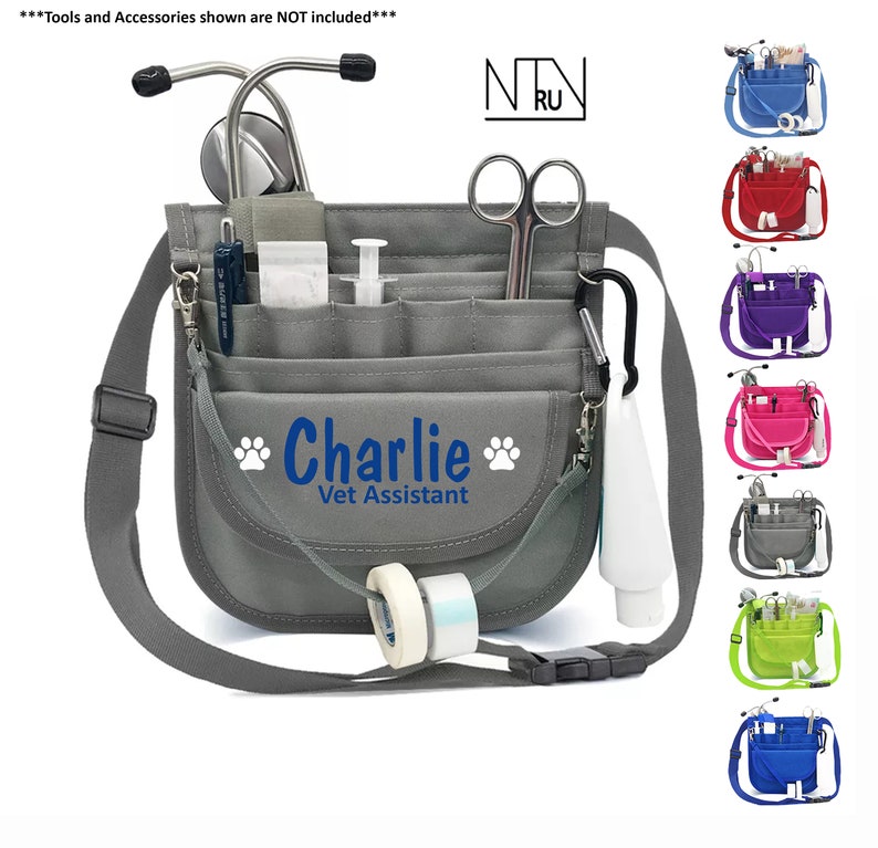 May include: Gray canvas veterinary technician bag with a blue embroidered name "Charlie" and the words "Vet Assistant". The bag has multiple pockets and a long adjustable strap. The bag is shown with a stethoscope, scissors, and other medical supplies.