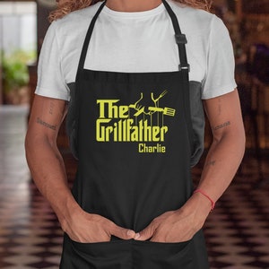 May include: Black apron with a yellow graphic that says "The Grillfather" with a hand holding a spatula and a fork. The name "Charlie" is written below the graphic.