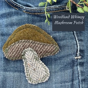 May include: A brown and green felt mushroom patch with the text "Woodland Whimsy Mushroom Patch" on a blue denim background.