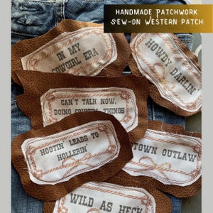 May include: A set of six brown leather patches with white fabric inserts and embroidered text. The patches feature western-themed sayings like "Howdy Darlin'" and "Can't Talk Now, Doing Cowgirl Things".
