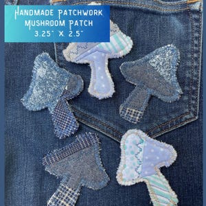 May include: Five handmade patchwork mushroom patches in various shades of blue and white, sewn onto a blue denim background. The patches are approximately 3.25 inches by 2.5 inches.