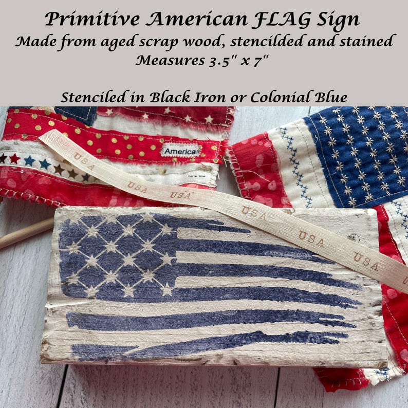 May include: Aged wood sign with a stenciled American flag design. The sign measures 3.5" x 7" and is stenciled in black iron or colonial blue. The image also shows a ribbon with "USA" printed on it and a fabric American flag.