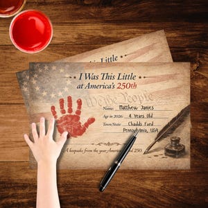 Op de afbeelding: Een rechthoekig papieren aandenken met een vervaagde Amerikaanse vlag op de achtergrond, een rode handafdruk en de tekst I Was This Little at America's 250th, We the People, Name: Matthew James, Age in 2026: 4 Years Old, Town/State: Chadds Ford, Pennsylvania, USA.