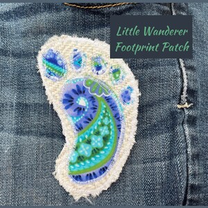 May include: A colorful, embroidered footprint patch with the text "Little Wanderer Footprint Patch" on a denim background. The patch features a paisley design in shades of blue and green, with a white, frayed edge.