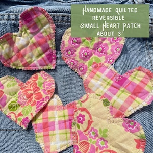 May include: Five handmade quilted reversible heart patches in pink, yellow, and green fabrics. The patches are about 3 inches in size and are arranged on a blue denim background. HANDMADE QUILTED REVERSIBLE SMALL HEART PATCH ABOUT 3" is written in white text on a green background.
