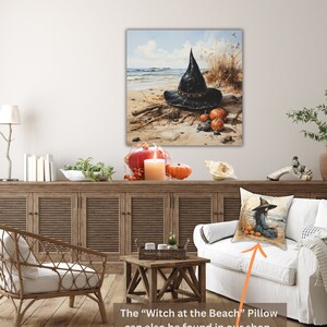 May include: A black witch's hat with a wide brim sits on a sandy beach with pumpkins and driftwood. The hat is decorated with a black band and a buckle. The beach is surrounded by tall grasses and a blue sky with white clouds.