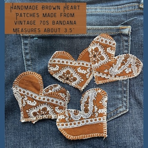 May include: Four brown heart-shaped patches made from vintage 70s bandanas. The patches are sewn together and measure about 3.5 inches across.